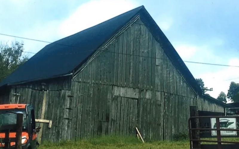 The weathered plank barn on the Shuford century farm, a tractor parked alongside it