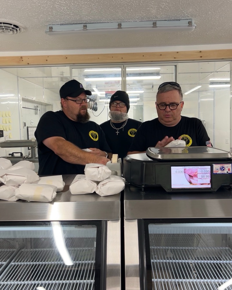 Whitt Shuford and two of his employees behind the meat counter at Whitt's Place, cuts wrapped in butcher paper on the case