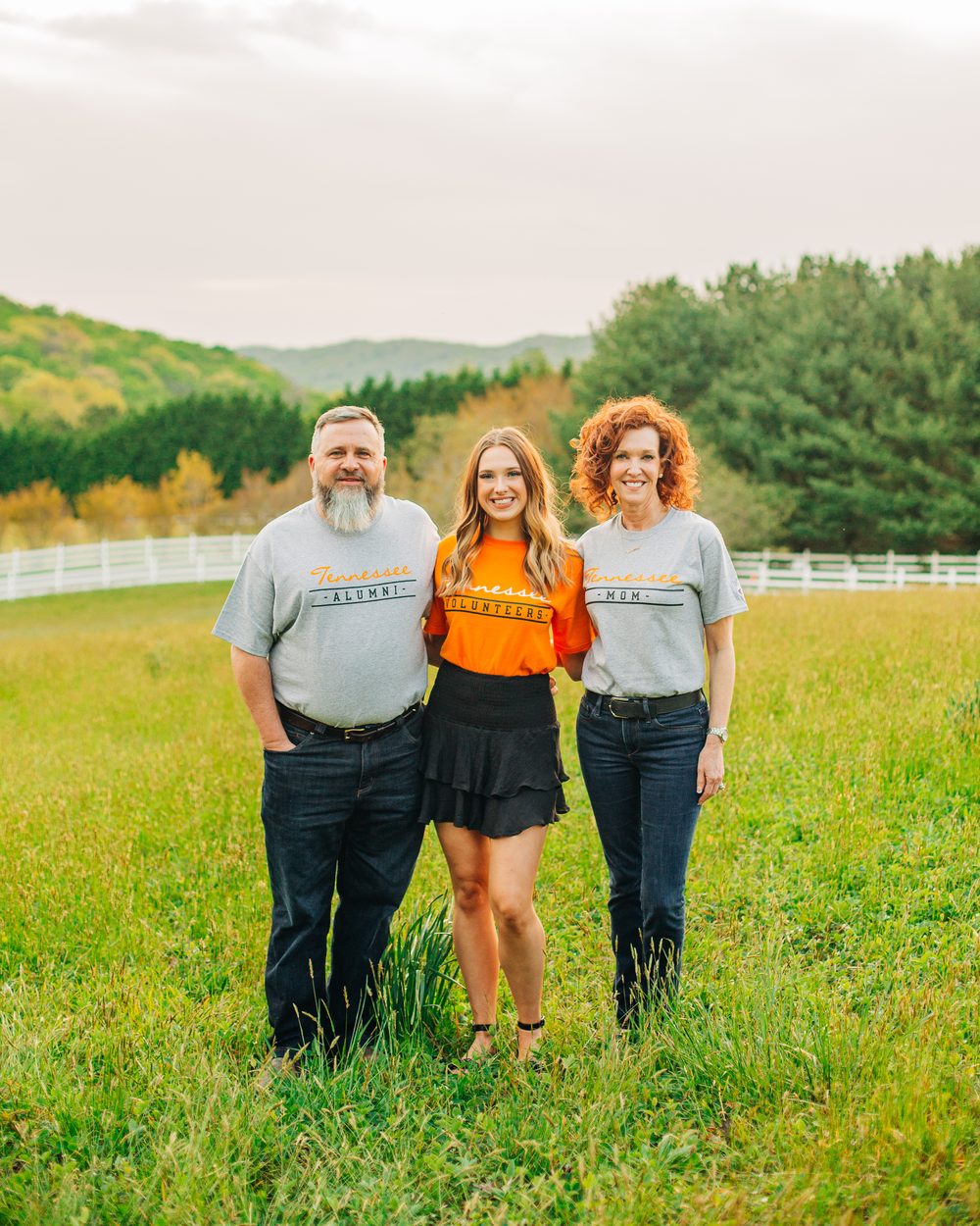 Whitt, Whittlee, and Dorothy standing in a pasture in Tennessee shirts reading Alumni, Volunteers, and Mom