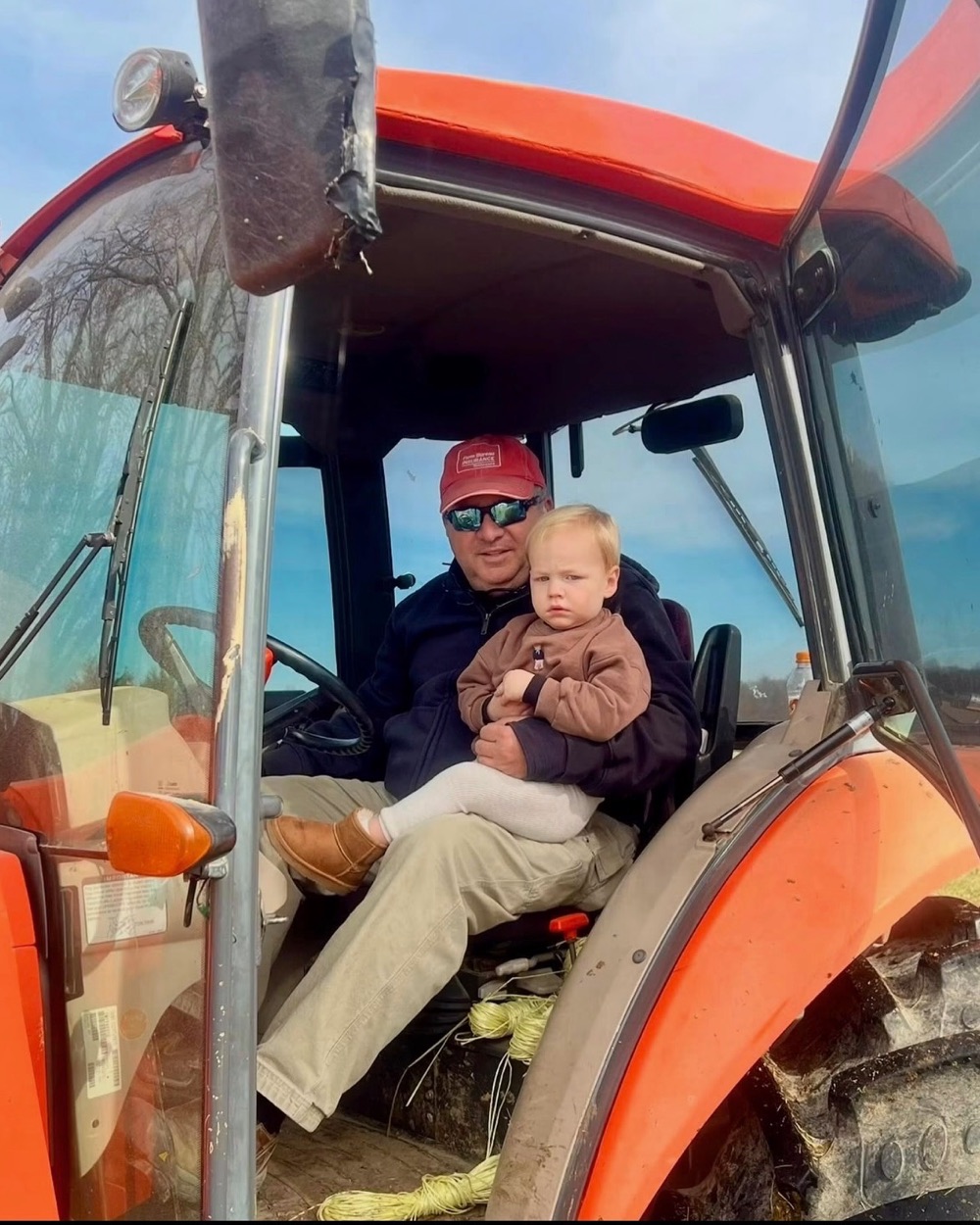 Whitt Shuford in the cab of his tractor with his grandson on his lap