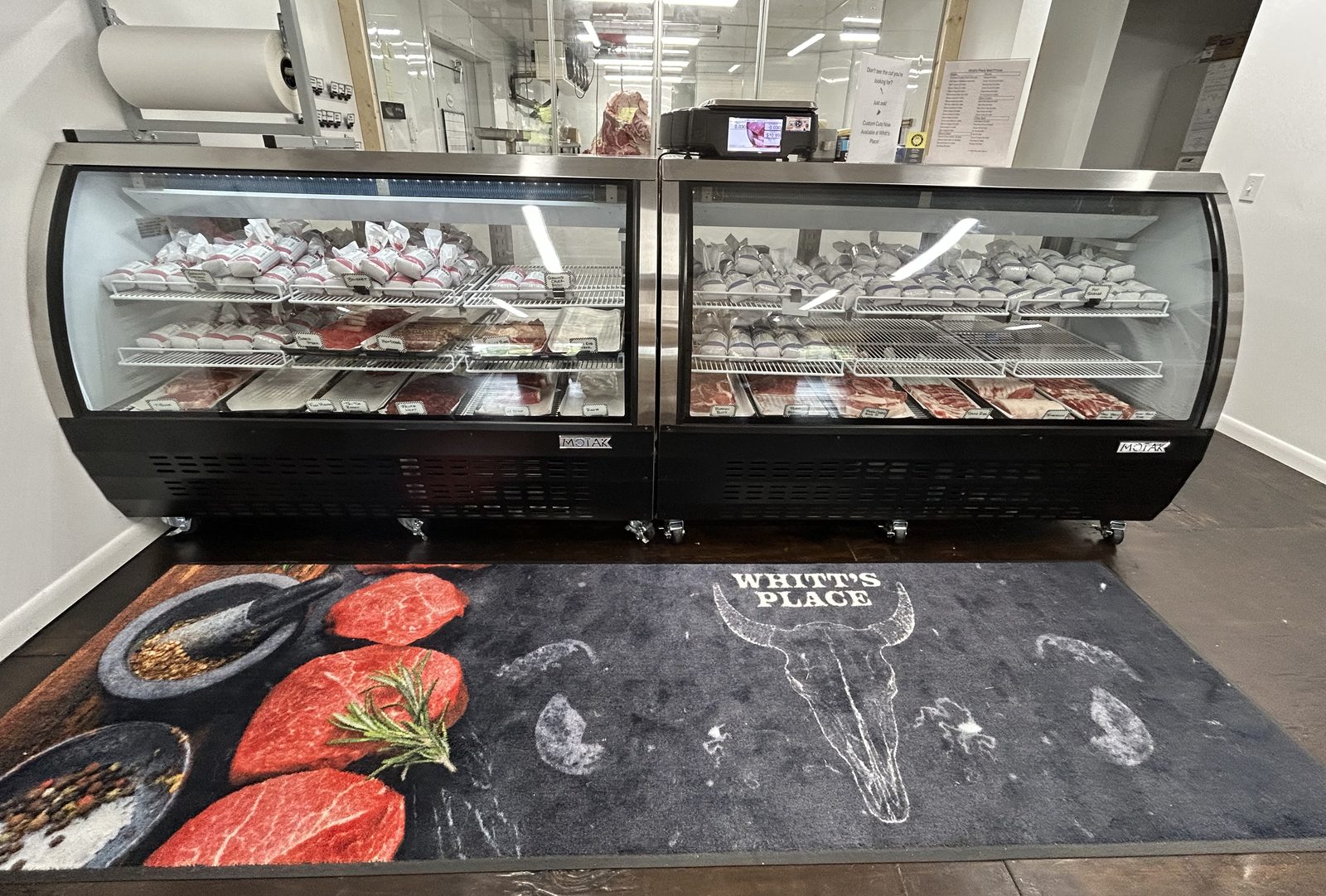 The retail case at Whitt's Place, stocked with beef and other cuts, the Whitt's Place mat on the floor in front of it