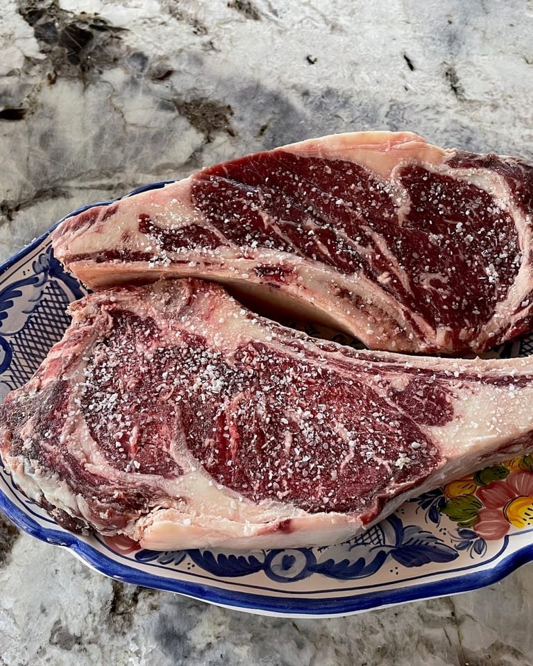 Two bone-in ribeye steaks from Whitt's Place beef, salted and ready to cook